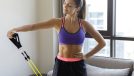 woman doing resistance band exercise, concept of at-home strength workouts for women to lose weight